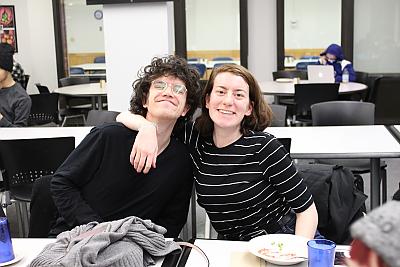 一名女学生和一名男学生在为参加多元化和包容性中心活动的学生举行的晚宴上对着镜头微笑. 左边的女学生搂着男学生. 