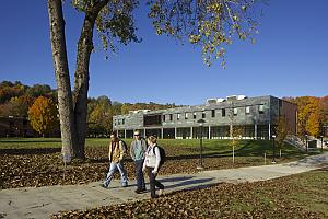 三名学生走在麦克法兰中心前的小路上，背景是秋天的颜色
