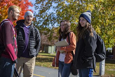 四名地标学院的学生站在户外，背景是秋叶