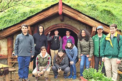 Students in front of the round door of a home on the Hobbiton movie set in New Zealand